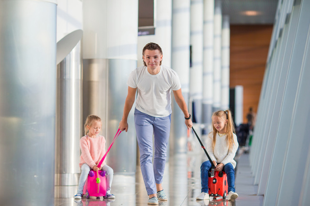 Счастливая семья с двумя детьми в аэропорту весело ждет посадки
 - Фото, изображение