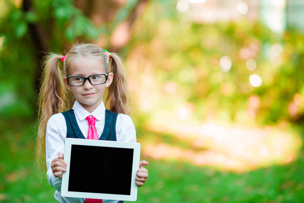 Adorable little girl holding tablet PC outdoors in autumn sunny day - Fotoğraf, Görsel