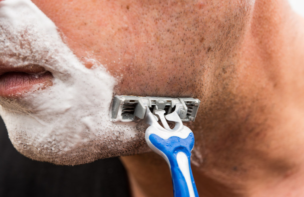 O homem faz a barba com a máquina-ferramenta
  - Foto, Imagem