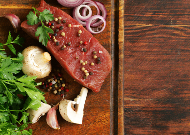 Carne fresca de res cruda en una tabla de cortar con verduras y especias
 - Foto, imagen