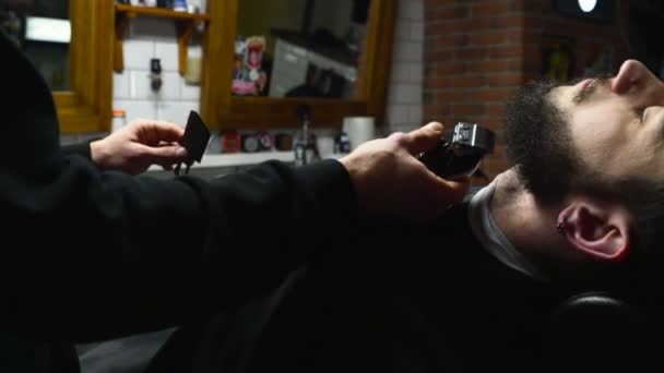 Barber shaves the beard of the client with clipper slow motion - Footage, Video