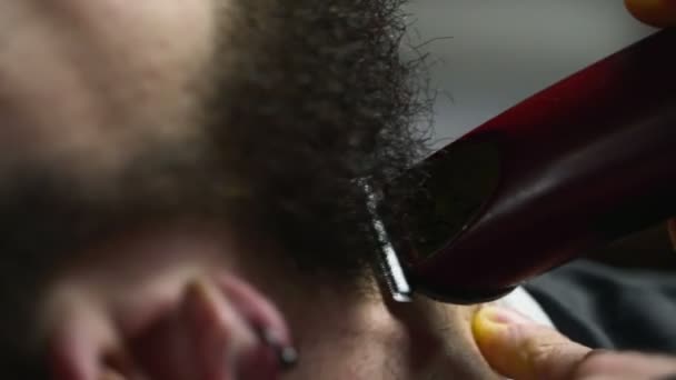 Holič oholí vousy klienta s zpomalené zastřihovače zblízka - Záběry, video