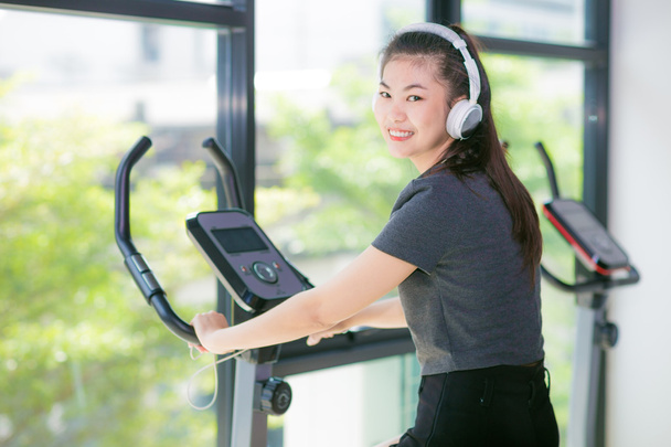 Mujer asiática haciendo ejercicio en el gimnasio en un cross trainer, Mujer entrenando en un club de fitness
 - Foto, Imagen
