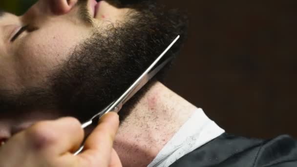 Fodrász csökkenti a szakáll hajat az ügyfél ollóval, lassú mozgás közelről - Felvétel, videó