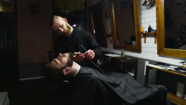 Peluquero afeita la barba del cliente con trimmer cámara lenta
 - Imágenes, Vídeo