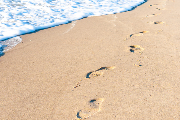 Jalanjälkiä hiekassa auringonlaskun aikaan. Kesämatkailun käsite
 - Valokuva, kuva