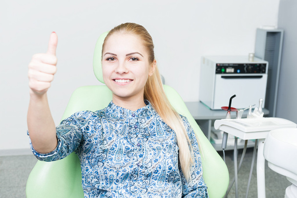 Relaxed female patient showing like on dentist chair - 写真・画像