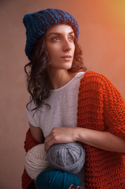 Жінка в трикотажному светрі і капелюсі тримає нитки
 - Фото, зображення