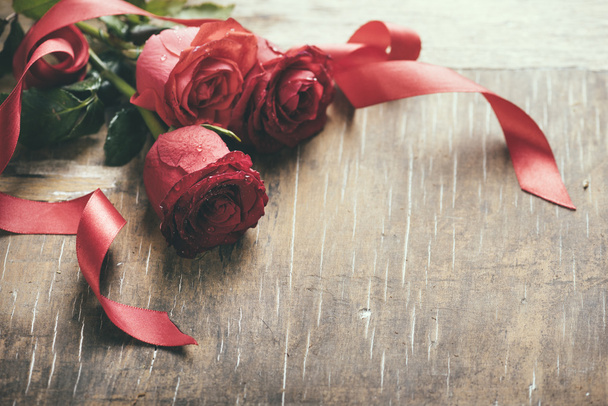 Punaiset ruusut punaisella nauhalla
 - Valokuva, kuva