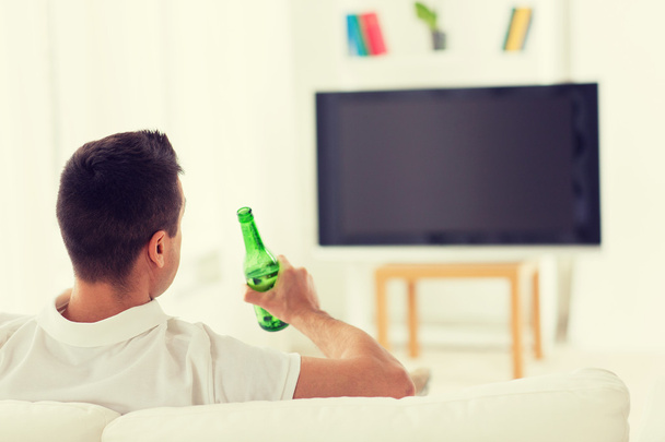 man watching tv and drinking beer at home - Photo, image
