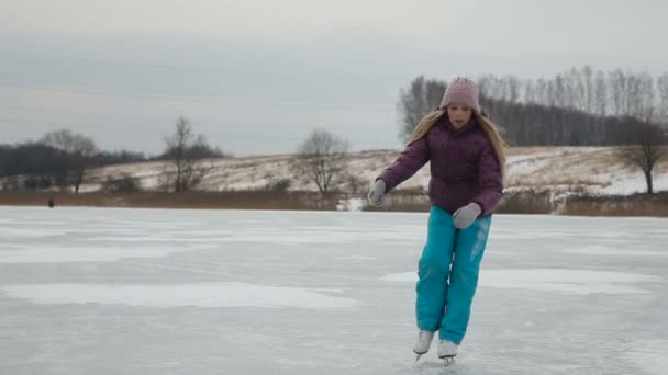 Młoda dziewczyna na łyżwach po zamarzniętym jeziorze - Materiał filmowy, wideo