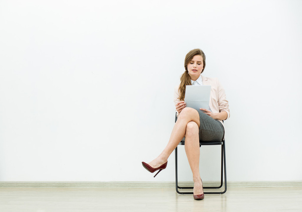 woman in office outfit waiting on a chair - Foto, afbeelding
