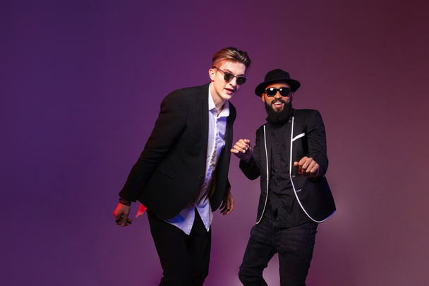 Two attractive cheerful young men in sunglasses dancing  - 写真・画像