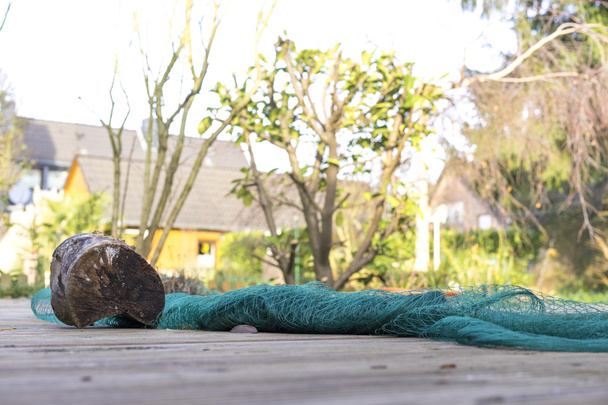 Aufgerolltes Fischernetz mit Baumstamm beschwert - Foto, Bild
