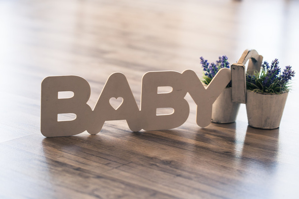 Слово baby деревянными буквами на полу с горшком лаванды
 - Фото, изображение