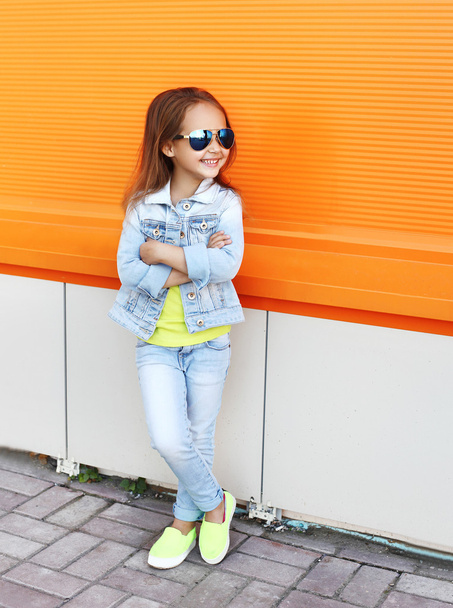 Красива усміхнена маленька дівчинка в сонцезахисних окулярах і джинсах
 - Фото, зображення