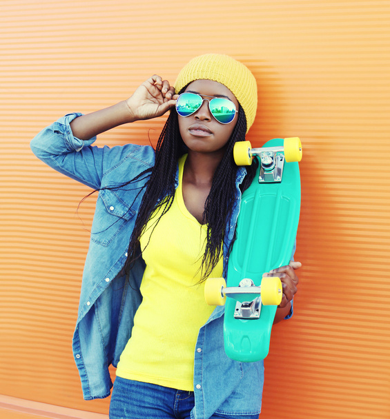 Fashion young african woman with skateboard in colorful clothes  - 写真・画像