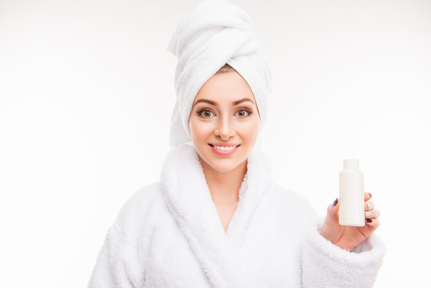 Pretty girl with towel on her head holding lotion - Foto, imagen