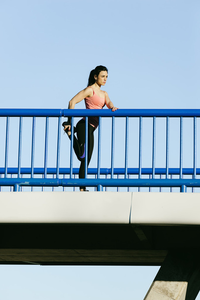 Young fitness woman runner stretching legs after run. - Foto, Bild