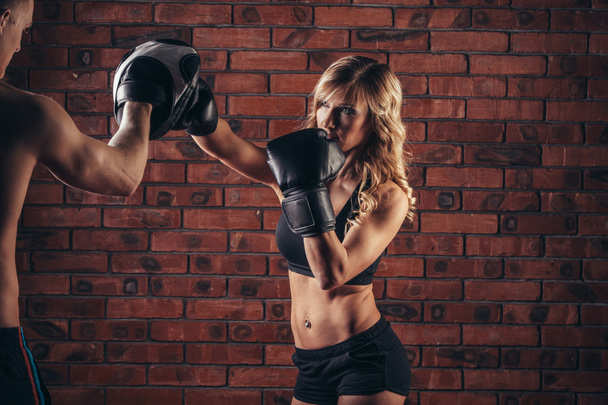 Cute brunette woman training with boxing gloves at the gym against brick wall - Foto, Imagem