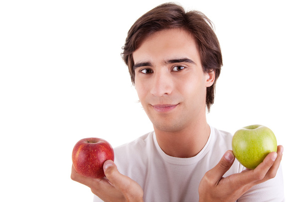 Πορτρέτο ενός νεαρού άνδρα με δύο μήλα στα χέρια τους: πράσινο και κόκκινο. Έννοια της επιλογής - Φωτογραφία, εικόνα