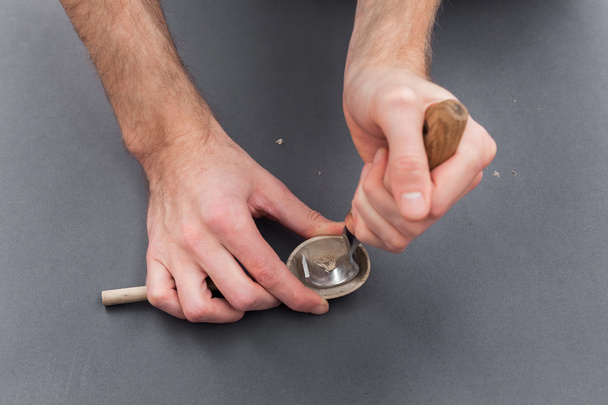 Man hands carving of a wooden spoon with hook knife on gray background - Fotoğraf, Görsel
