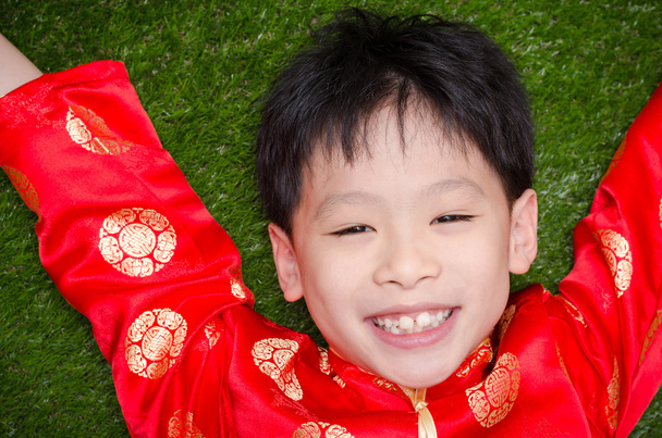芝生に横になっている中国の衣装を着た少年 - 写真・画像