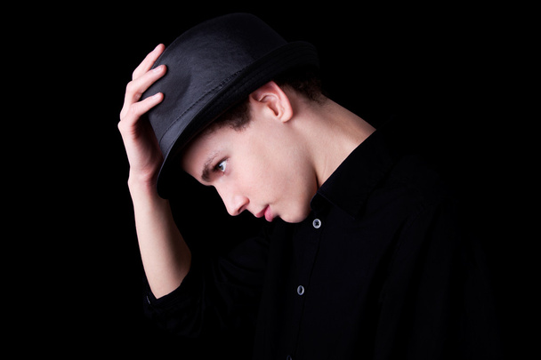 Young man wearing a hat over black background, studio shot - Photo, Image