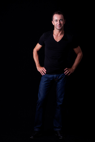 Portrait of a handsome middle-age man smiling, on black background. Studio shot - Fotó, kép