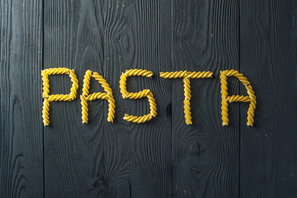 Fusilli pasta on a old wooden background. Italian cuisine. - Фото, зображення