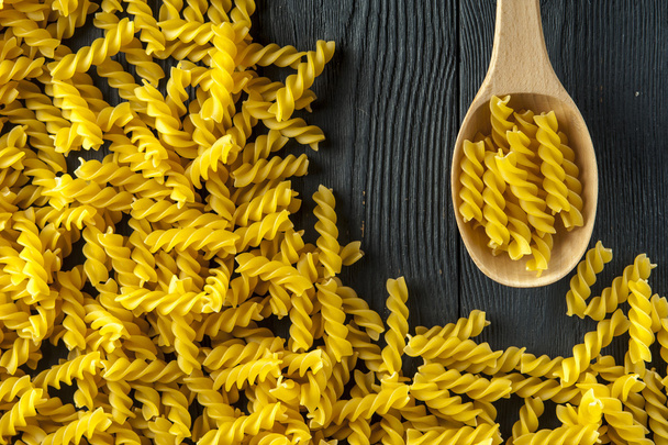 Fusilli pasta and spoon on old wooden background. Italian cuisine. - Foto, imagen