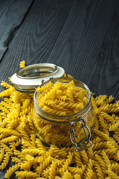Pasta fusilli in a jar on wooden background. Italian cuisine. - Fotografie, Obrázek