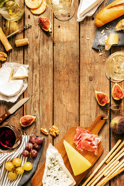 Different kinds of cheeses, wine, baguettes, fruits and snacks - Foto, Imagen
