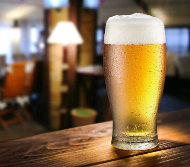 Glass of light beer on the glass bar counter. - 写真・画像