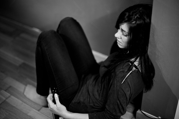 Femme assise sur le sol tenant une bouteille de vin noir et blanc déprimé
 - Photo, image
