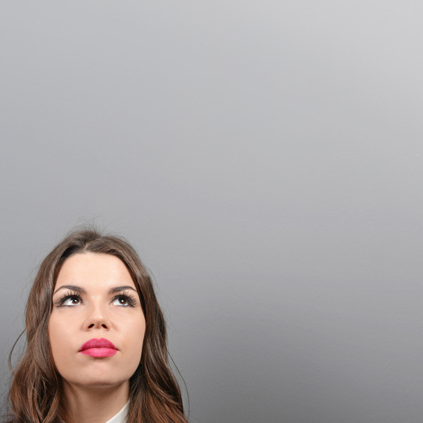 Beautiful woman looking at blank area against  gray background - Photo, Image