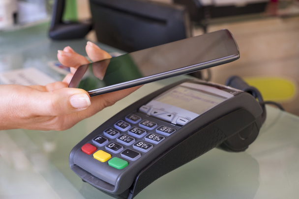 Woman paying with NFC technology on smartphone - Zdjęcie, obraz