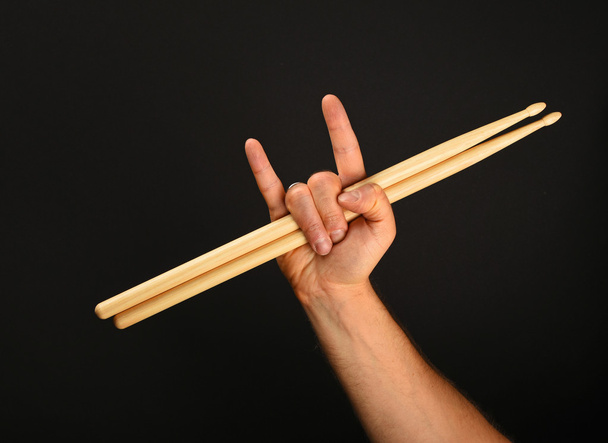 Man hand with drumsticks and devil horns over black - Fotografie, Obrázek
