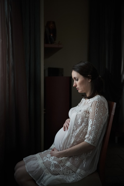 Pregnant woman sitting on a chair - Фото, изображение