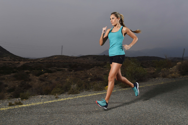 jonge passen sport vrouw buitenshuis draait op asfaltweg in berg fitnesstraining - Foto, afbeelding