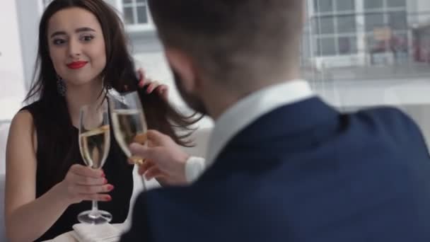 Goed geklede paar roosteren champagne fluiten in restaurant - Video