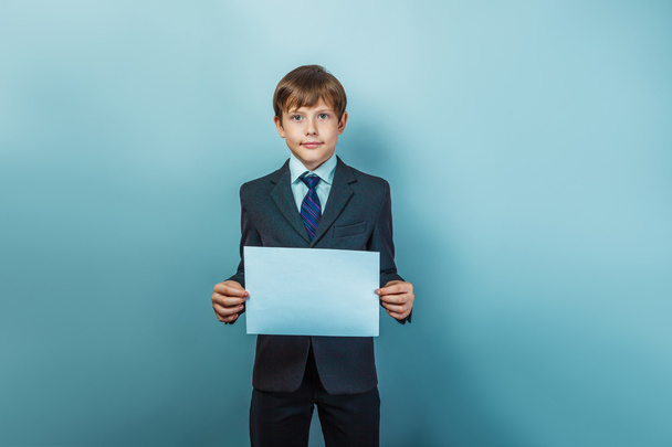 ein zwölfjähriger Junge mit europäischem Aussehen in einem Anzug mit einem Rohling - Foto, Bild