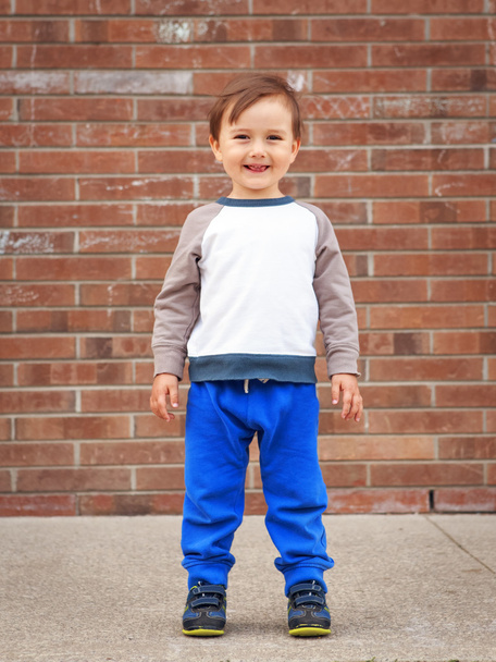 Toddler boy by brick wall laughing - Foto, Imagen
