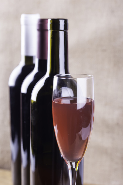 стакан розового вина на фоновых бутылках
 - Фото, изображение