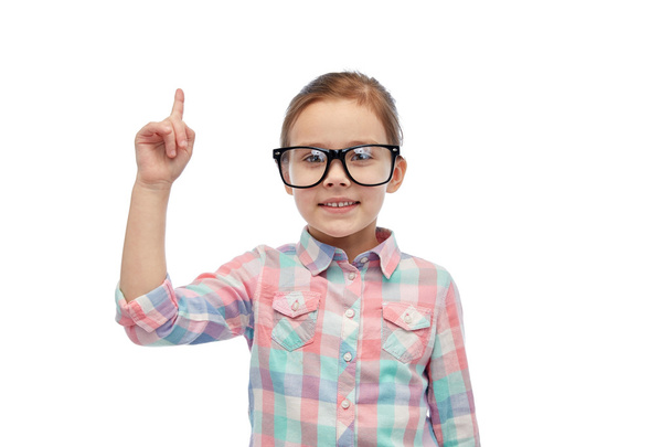 happy little girl in eyeglasses pointing finger up - 写真・画像