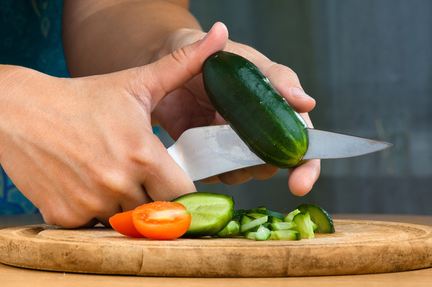 hands slicing cucumbers and tomatoes for salad - 写真・画像