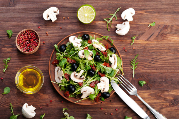 Salad with arugula, leaf mash, olives, sun-dried tomatoes and raw mushrooms. The concept of diet vegetarian food homemade - Φωτογραφία, εικόνα