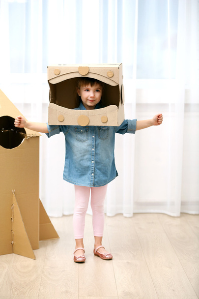 Girl playing with cardboard space rocket - 写真・画像