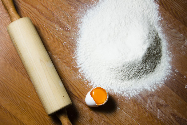 Ingredience pro přípravu těsta na dřevěný stůl. Mouku, vejce a váleček. - Fotografie, Obrázek
