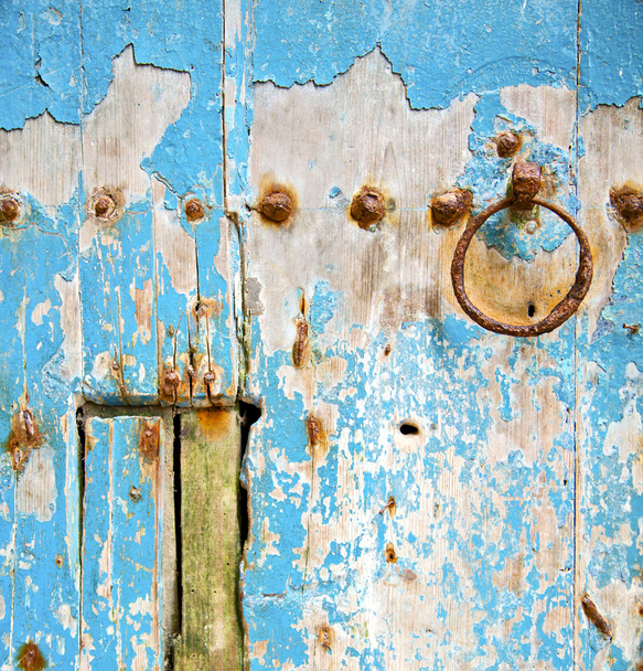 rusty metal     nail dirty stripped paint in the blue wood door  - Photo, image
